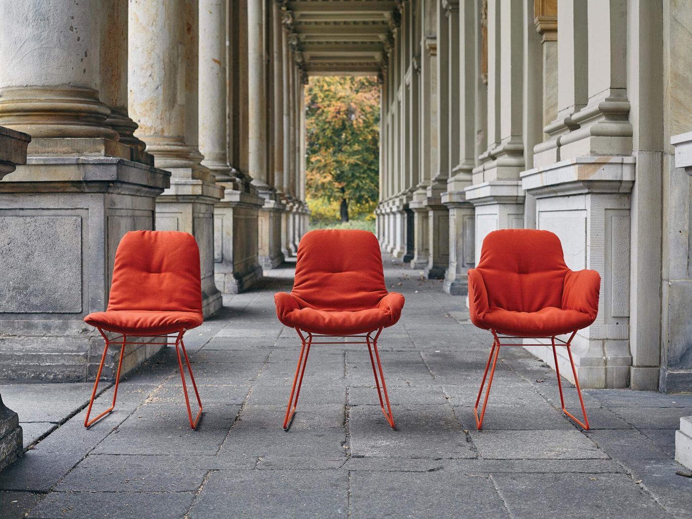 Drei Leya Chairs in Rot unter einer Kolonnade in Berlin