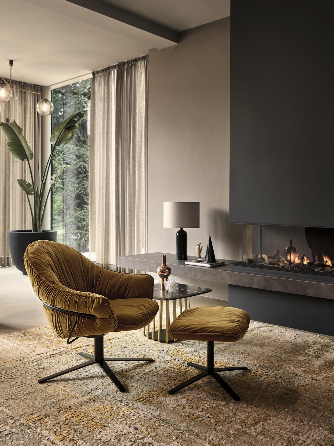 Freifrau Marie Lounge Chair mit Ottoman vor einem Kamin in einem hellen Wohnraum